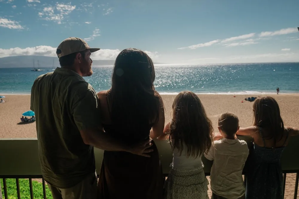 Family watches the beach and ocean from a balcony at Outrigger Kaanapali Beach Resort.