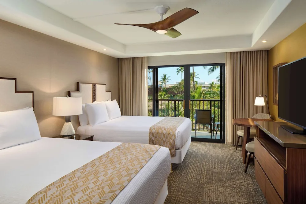 Two-queen guest room with balcony and palm views at Outrigger Kaanapali Beach Resort.