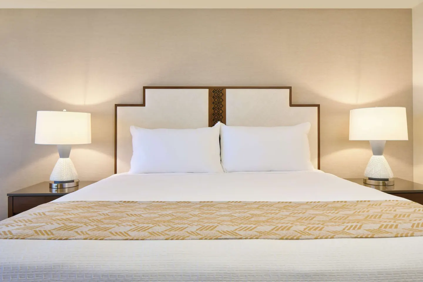 King bed with white pillows and matching bedside lamps at Outrigger Kaanapali Beach Resort.