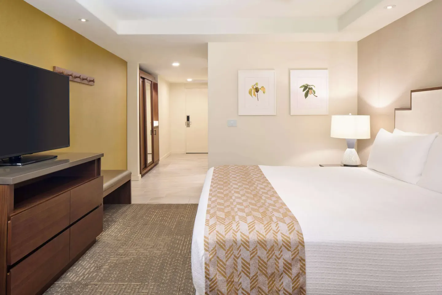 Guest room with king bed, TV dresser, and entry hallway at Outrigger Kaanapali Beach Resort.