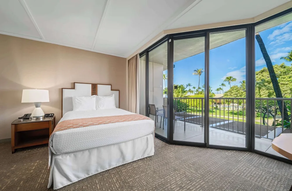 King bed guest room with wide balcony windows at Outrigger Kaanapali Beach Resort.