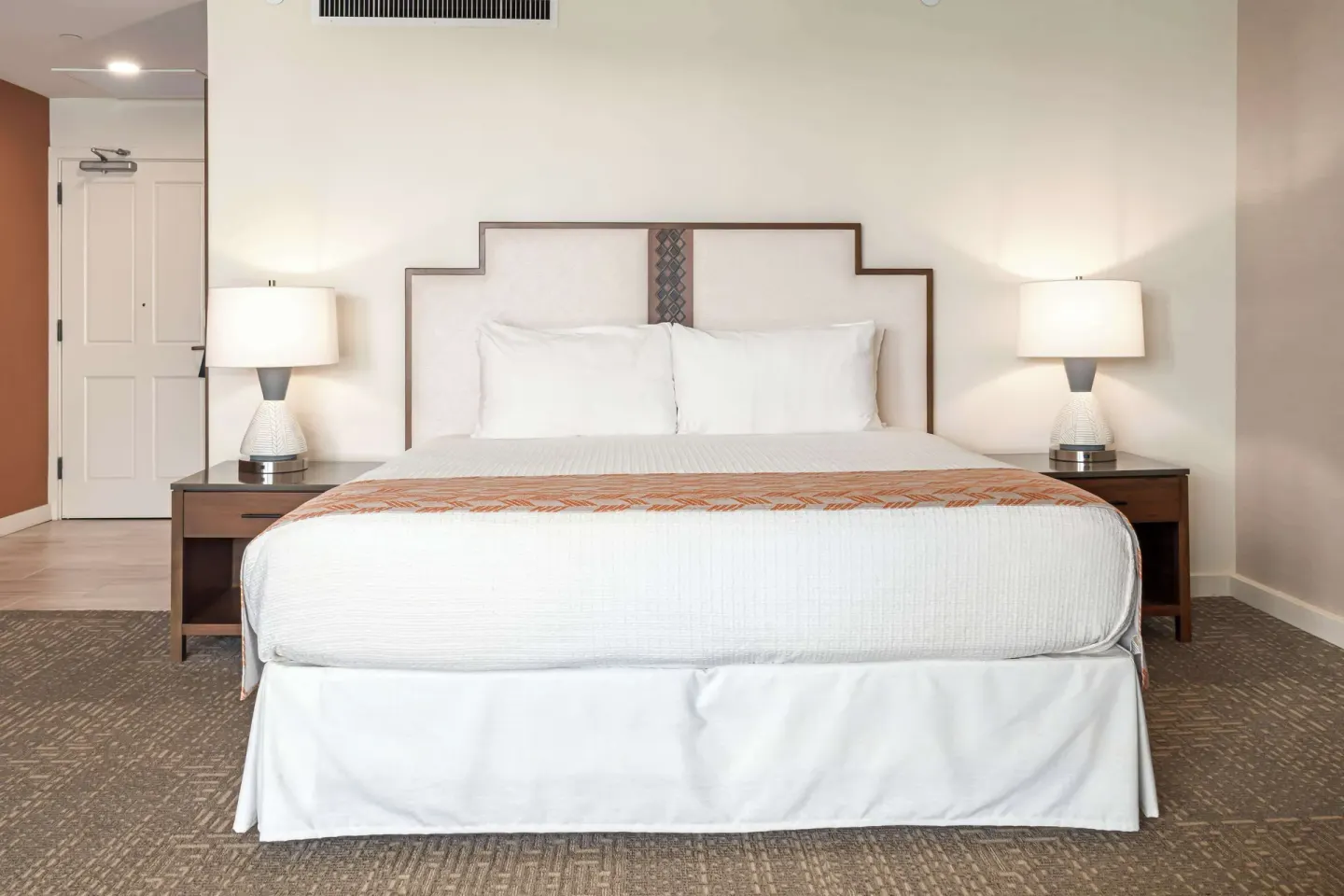 King bed with bedside lamps in a guest room at Outrigger Kaanapali Beach Resort.
