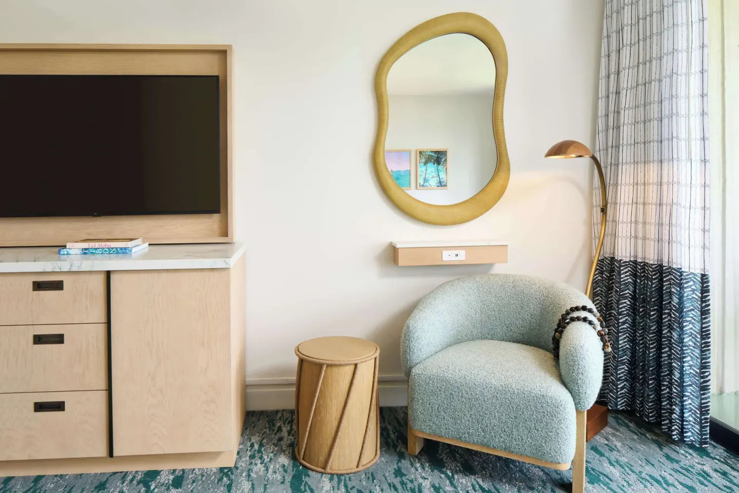 Guest room sitting area with TV, mirror and lounge chair at Outrigger Kaanapali Beach Resort.