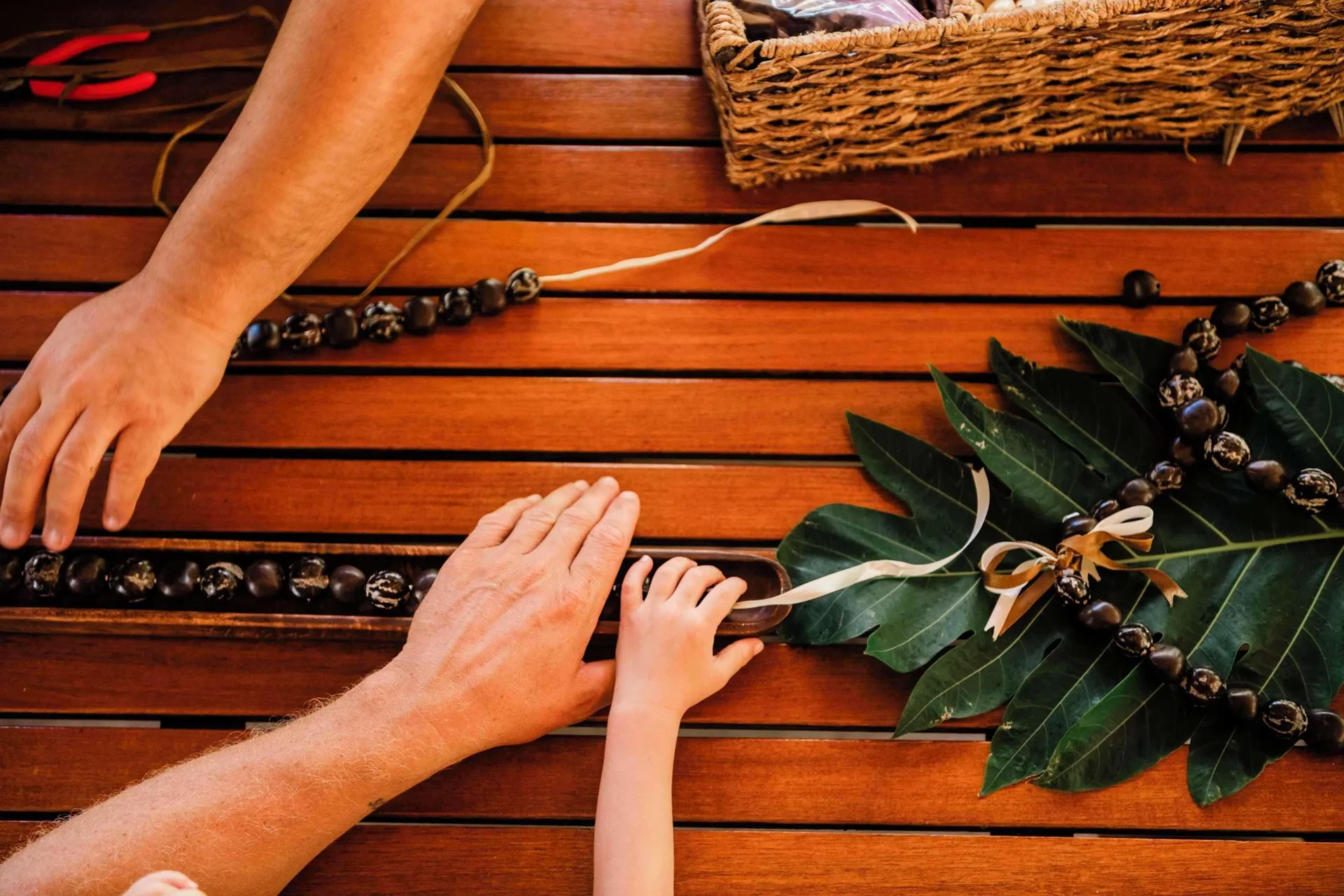 Hands arranging nut lei and leaves on a table at Outrigger Kaanapali Beach Resort.