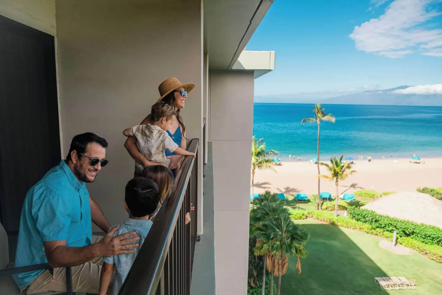 Family on an ocean-view balcony at Outrigger Kaanapali Beach Resort overlooking the beach.