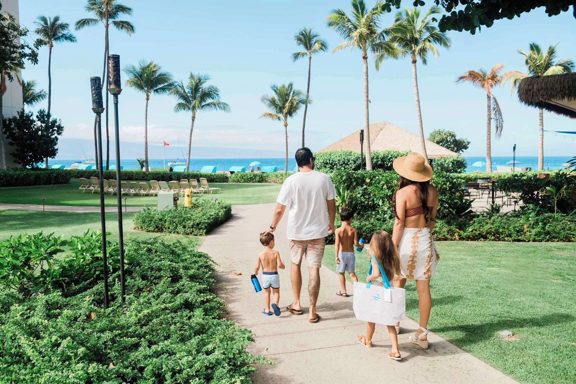 Family walking through palm-lined resort grounds at Outrigger Kaanapali Beach Resort.