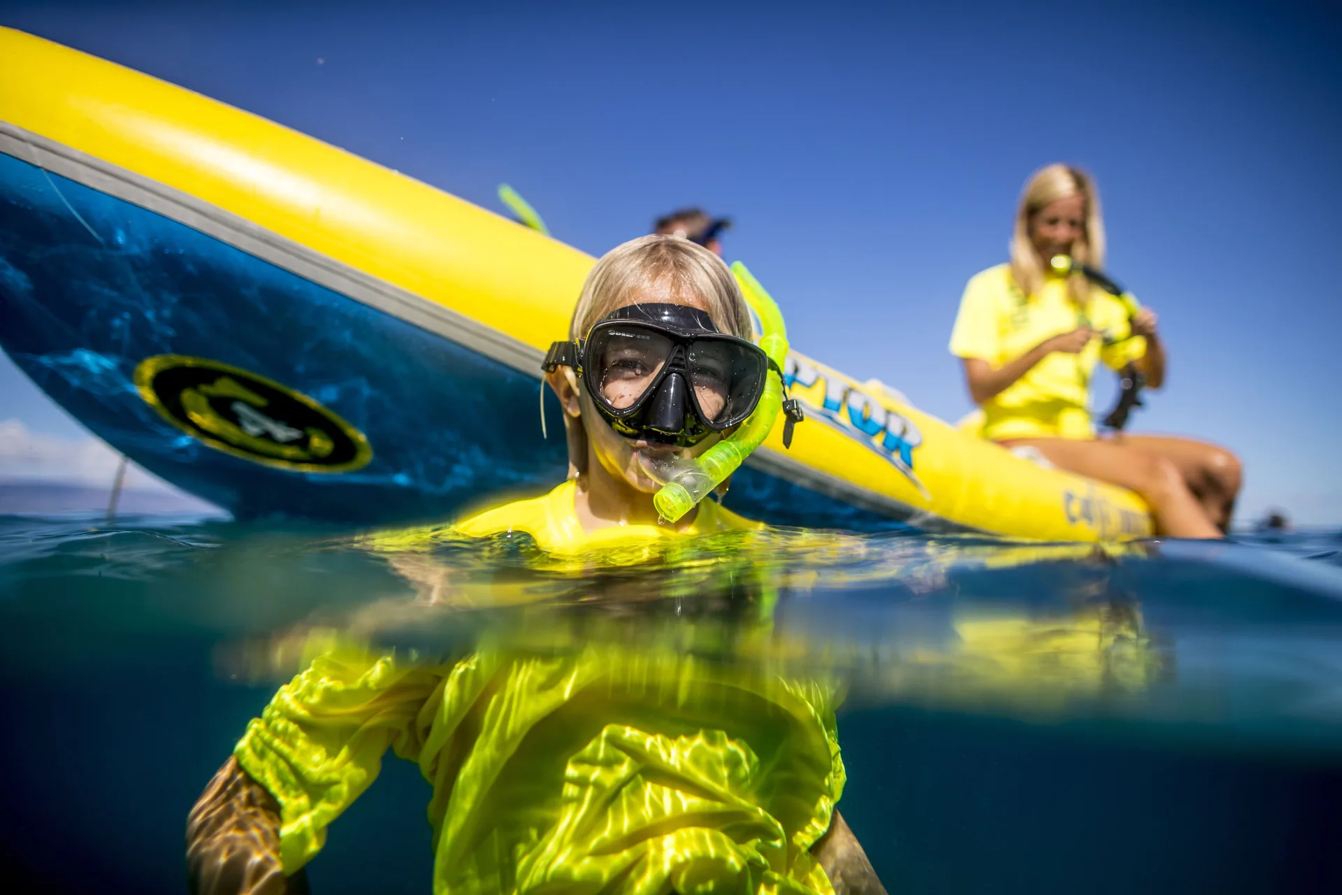 Child snorkeling beside an outrigger canoe at Outrigger Kaanapali Beach Resort.