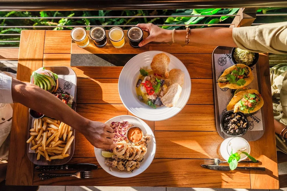 Shared plates, tacos, fries and beer flights on a patio table at Outrigger Kaanapali Beach Resort.