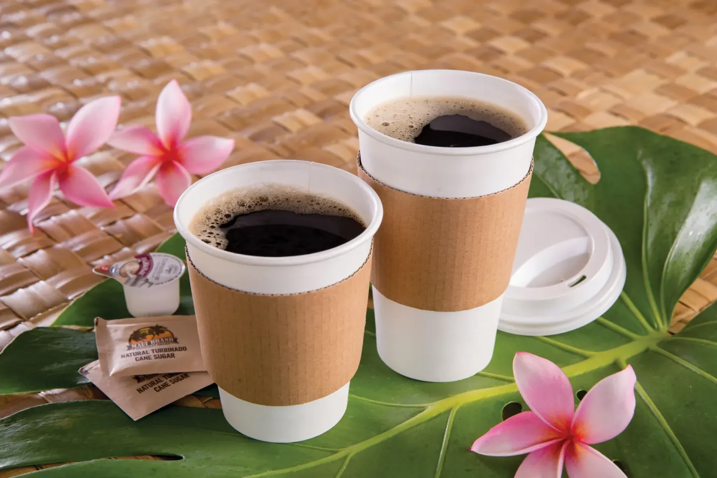Two takeaway coffees sit on tropical leaves at Outrigger Kaanapali Beach Resort.