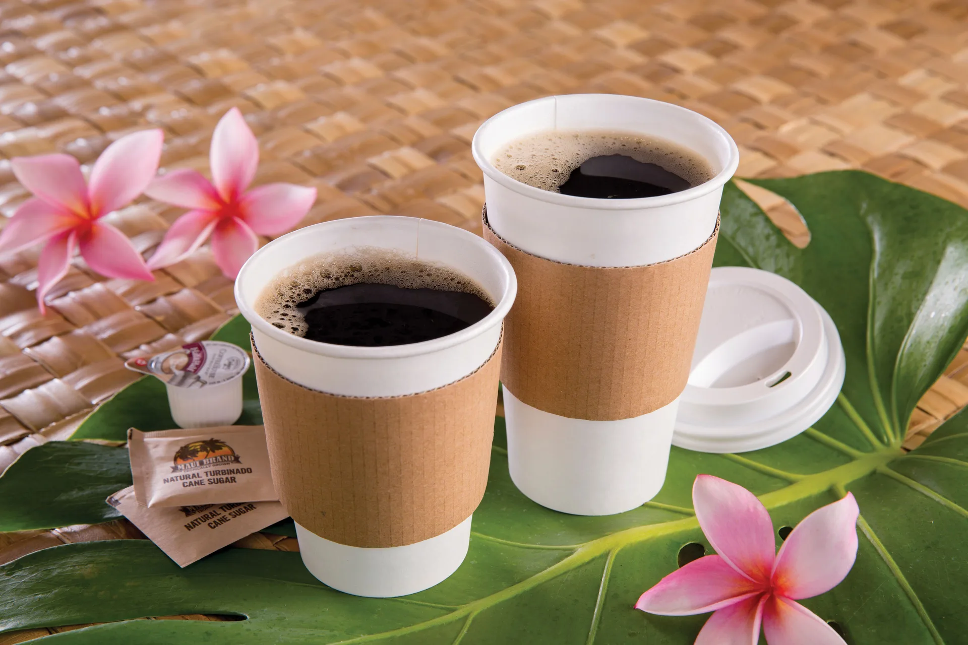 Two takeaway coffees sit on tropical leaves at Outrigger Kaanapali Beach Resort.