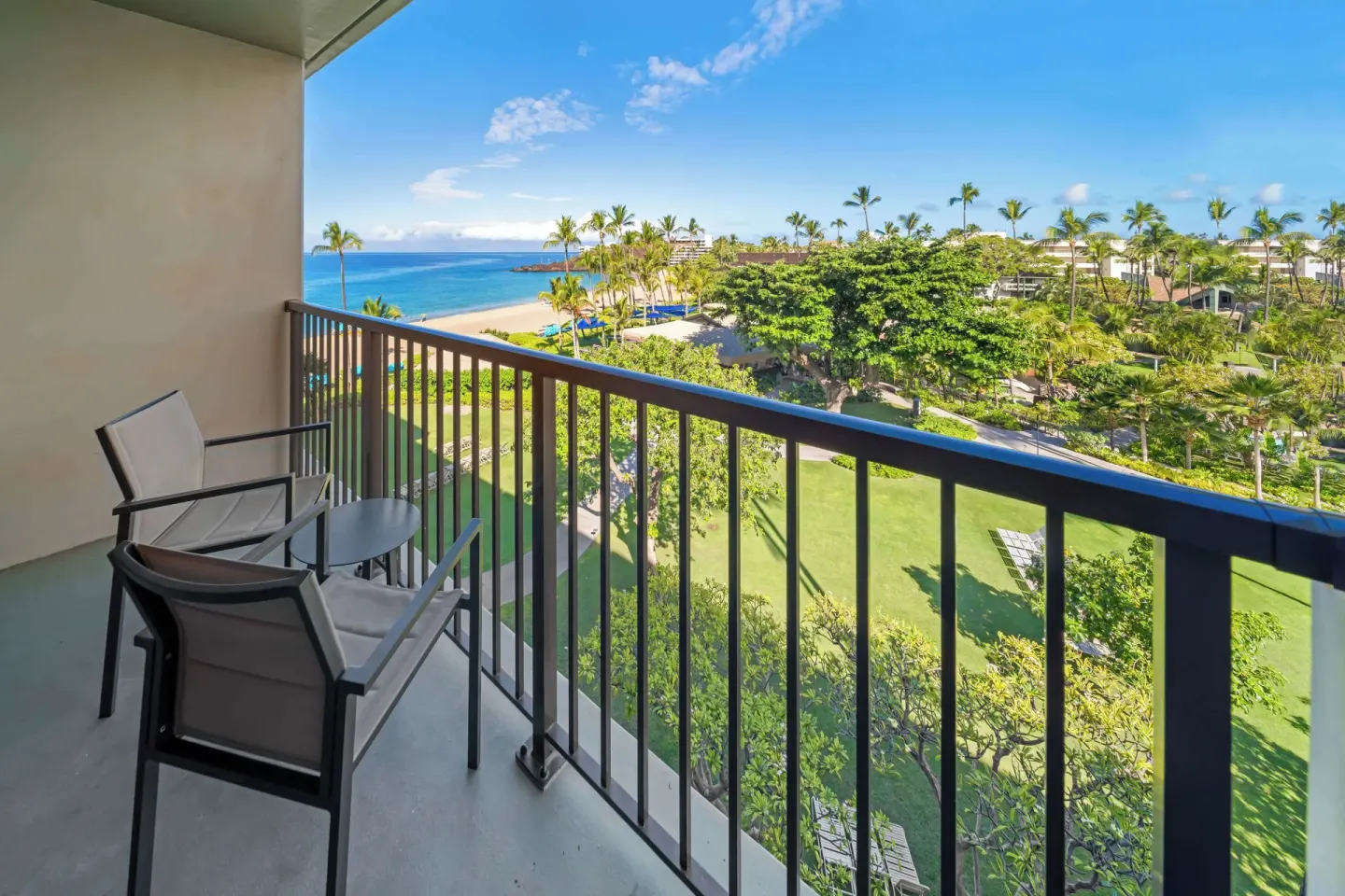 Balcony with chairs, ocean, beach, and gardens at Outrigger Kaanapali Beach Resort.