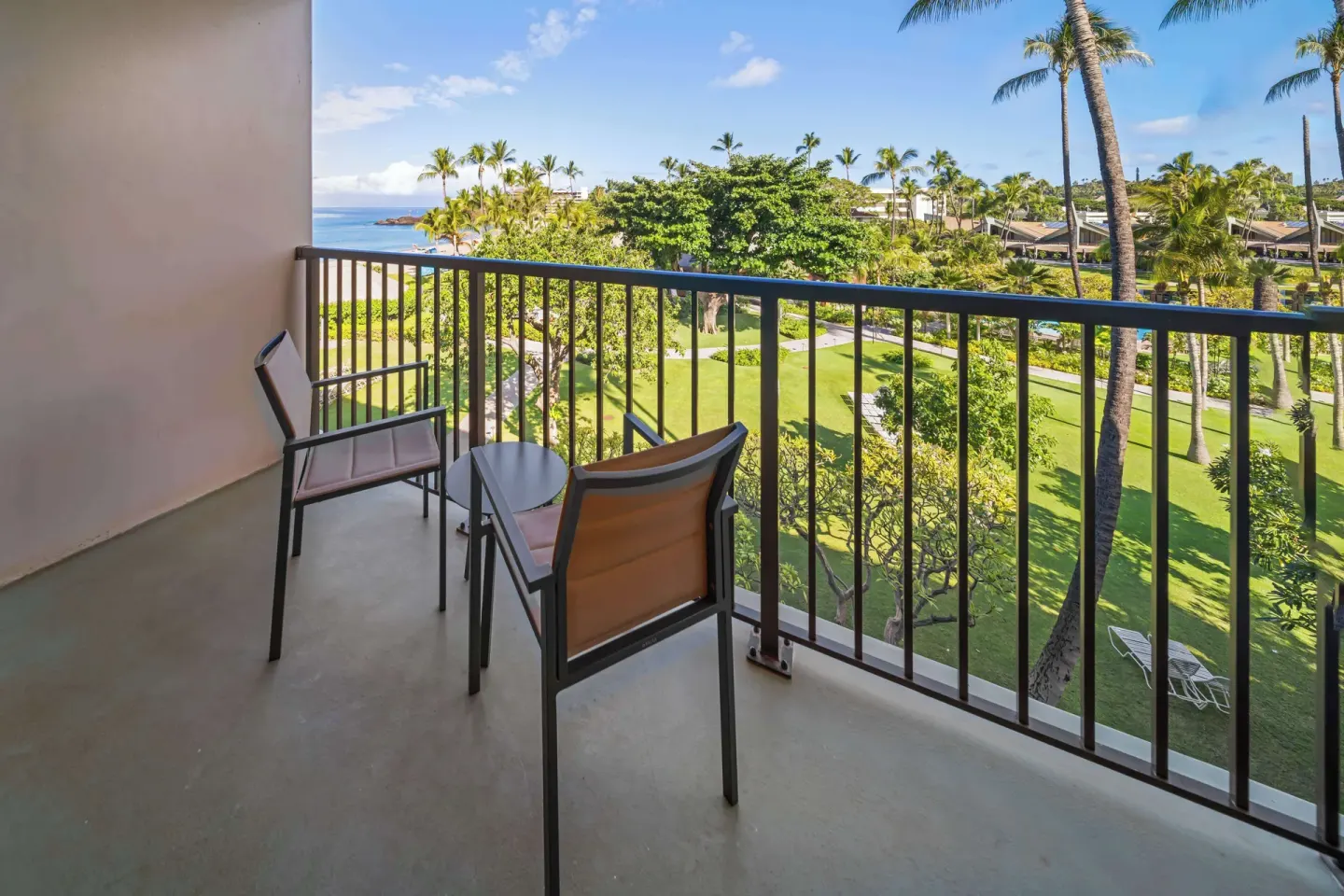 Furnished balcony overlooking lawns, palms, and ocean at Outrigger Kaanapali Beach Resort.
