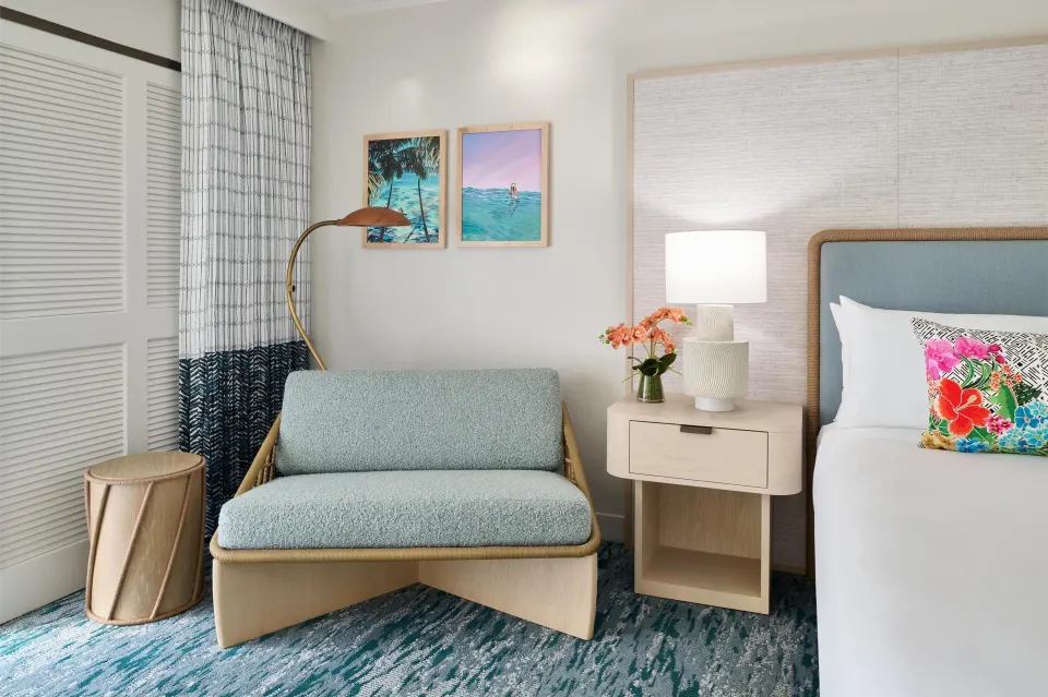 Seating area beside a king bed in a Signature Room at Outrigger Kaanapali Beach Resort.