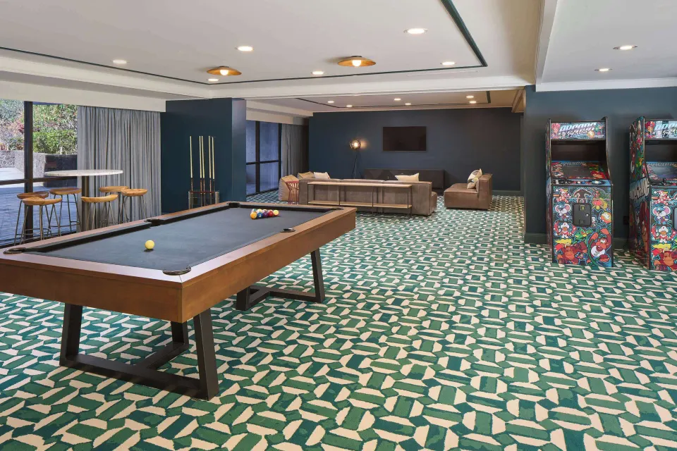 Game room with pool table, arcade games, and lounge seating at Outrigger Kona Resort and Spa.