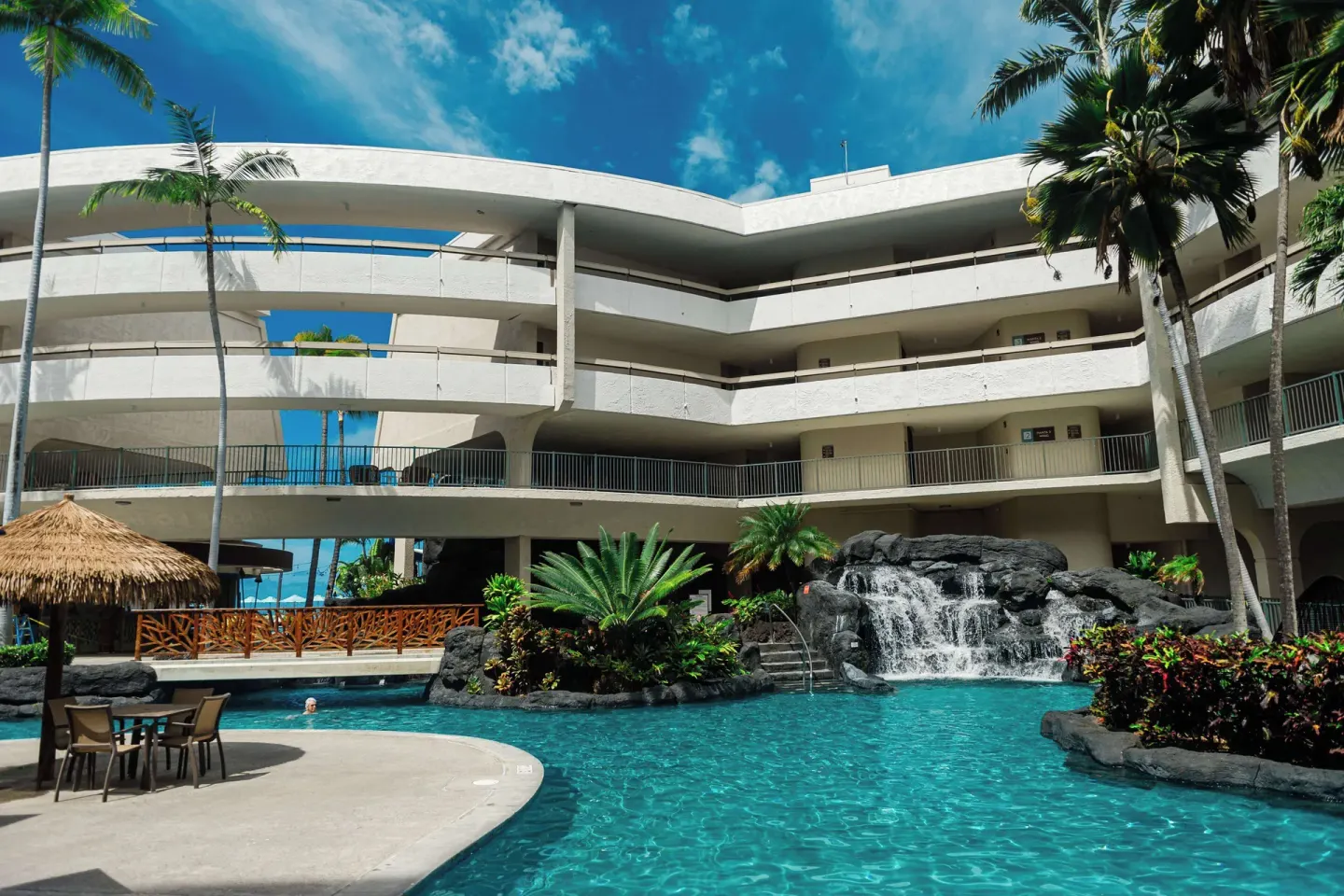 Lagoon-style pool with waterfall and palms at Outrigger Kona Resort and Spa.