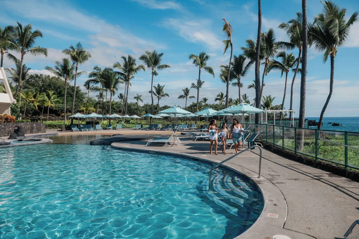 Oceanfront pool with palm trees and loungers at Outrigger Kona Resort and Spa.