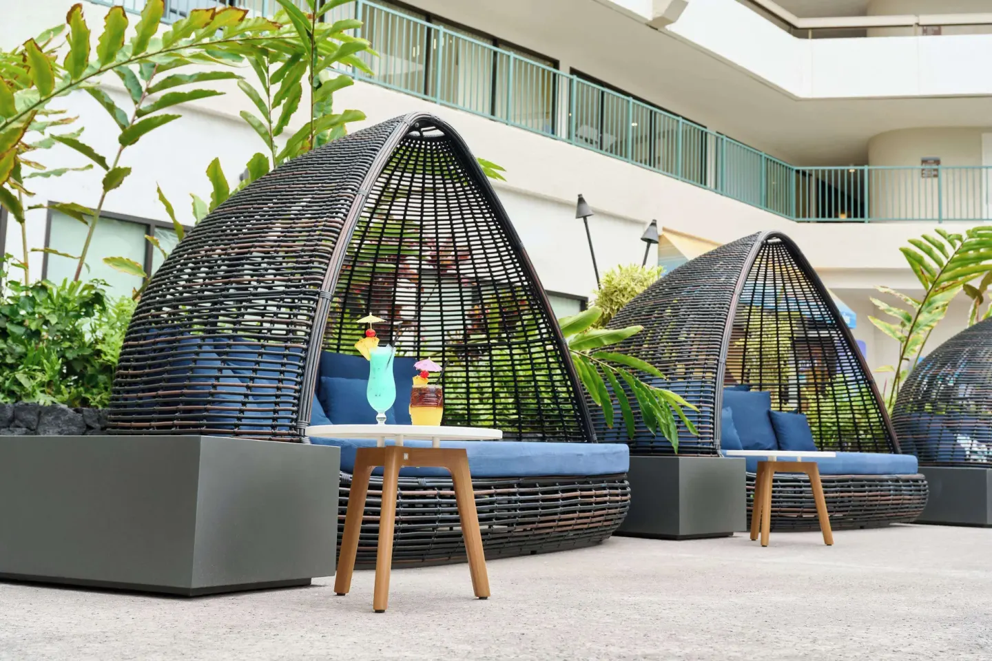 Pool cabanas with blue cushions and tropical drinks at Outrigger Kona Resort and Spa.