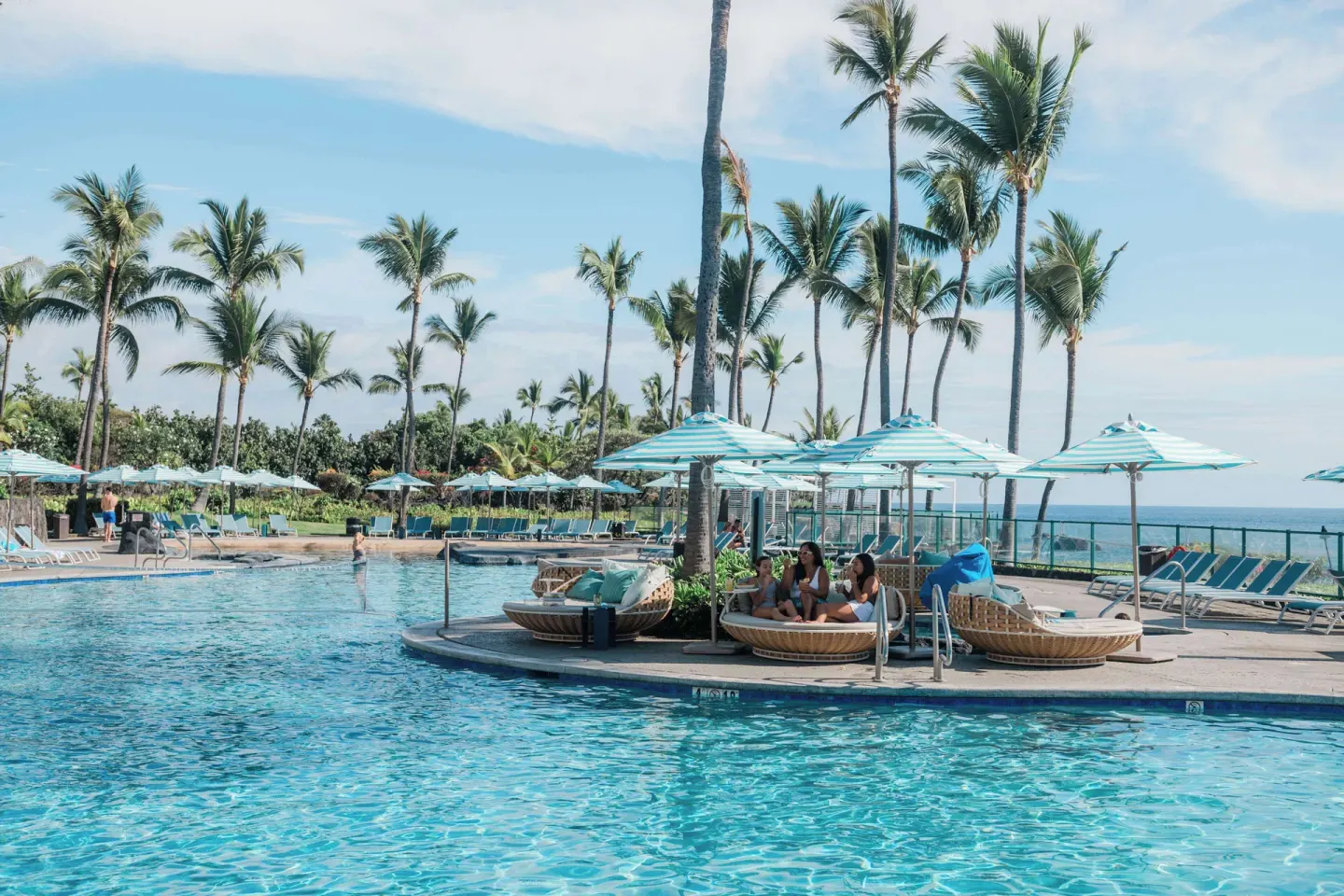 Poolside cabanas and umbrellas by the water at Outrigger Kona Resort and Spa.