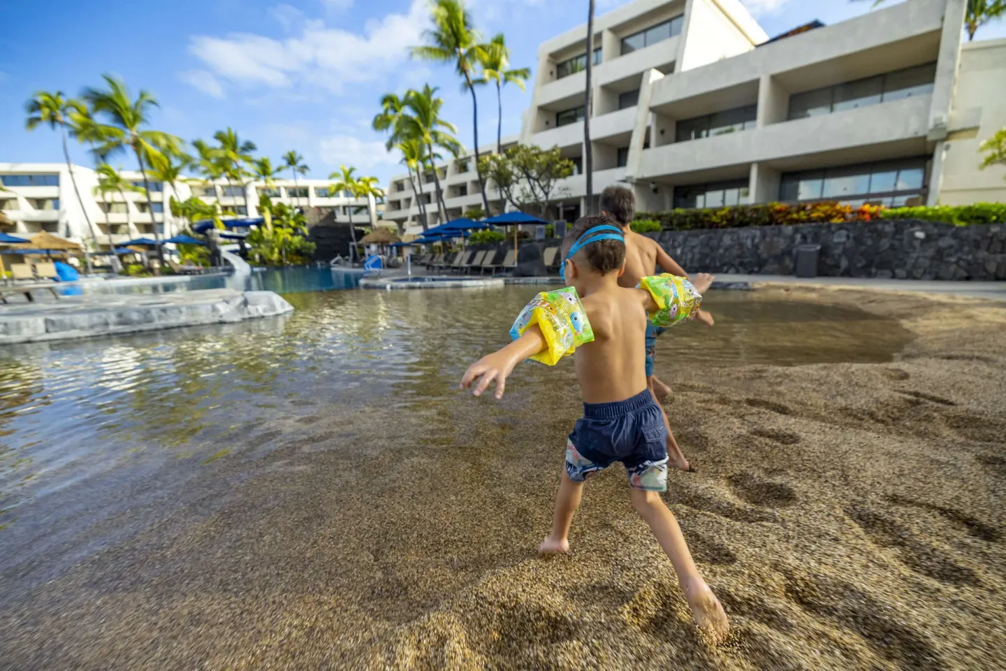 Children enter the sandy-edge pool at Outrigger Kona Resort and Spa.