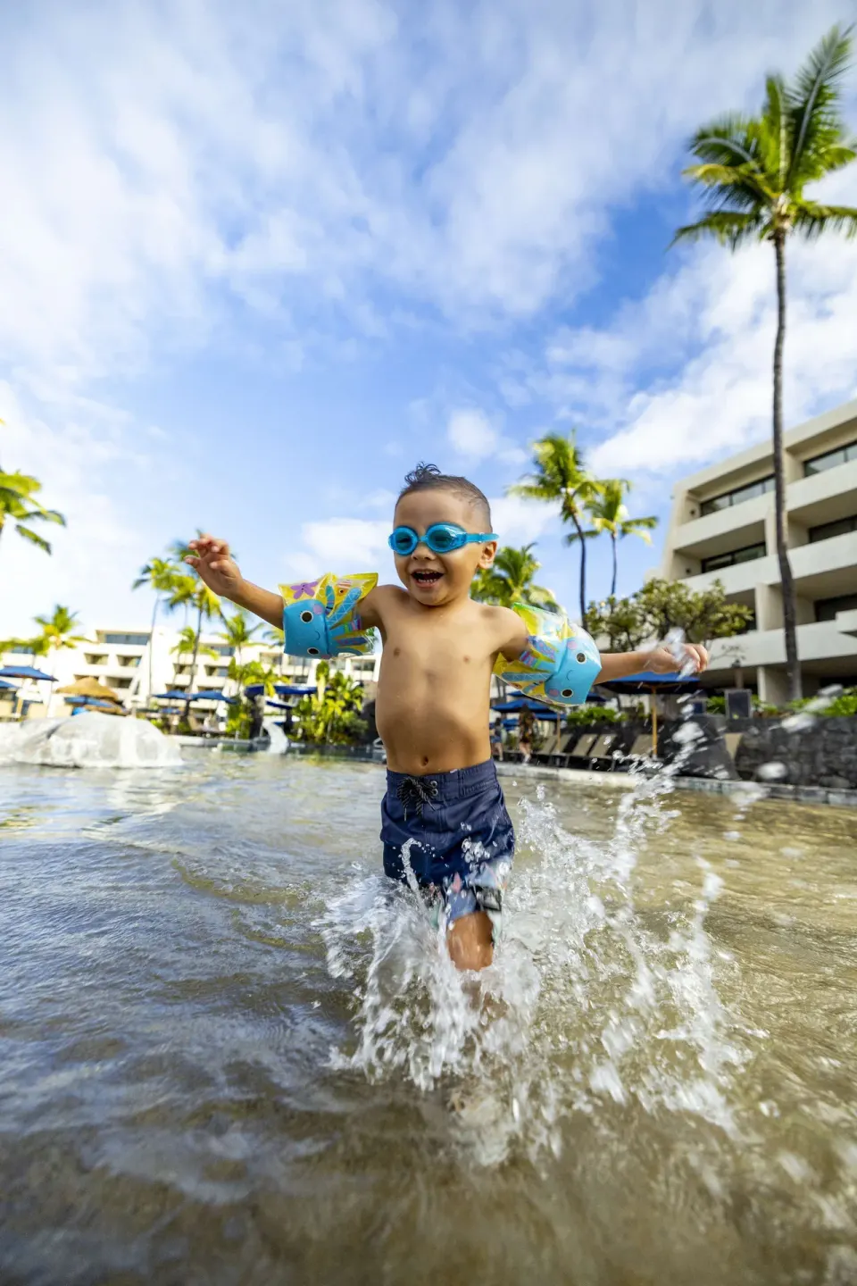 Child splashes through shallow pool water at Outrigger Kona Resort and Spa.