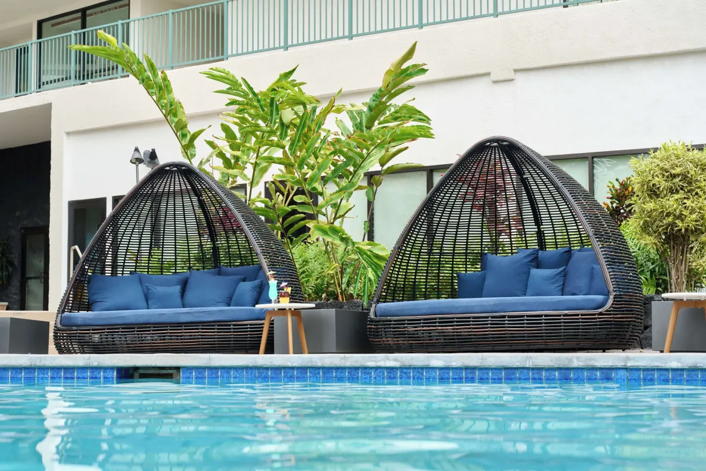 Wicker pool cabanas with blue cushions beside the water at Outrigger Kona Resort and Spa.