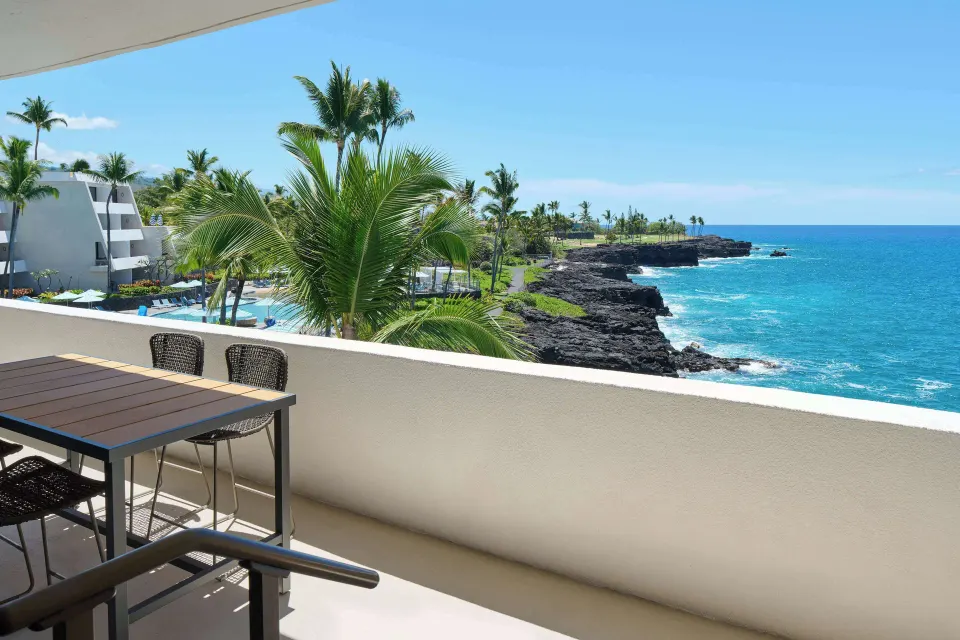 Deluxe Ocean Front Suite balcony with dining table and coastline view at Outrigger Kona Resort and Spa.