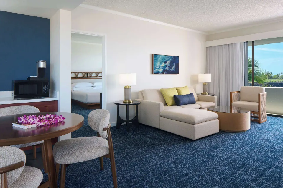 Deluxe Ocean Front Suite living area with dining table and sofa at Outrigger Kona Resort and Spa.