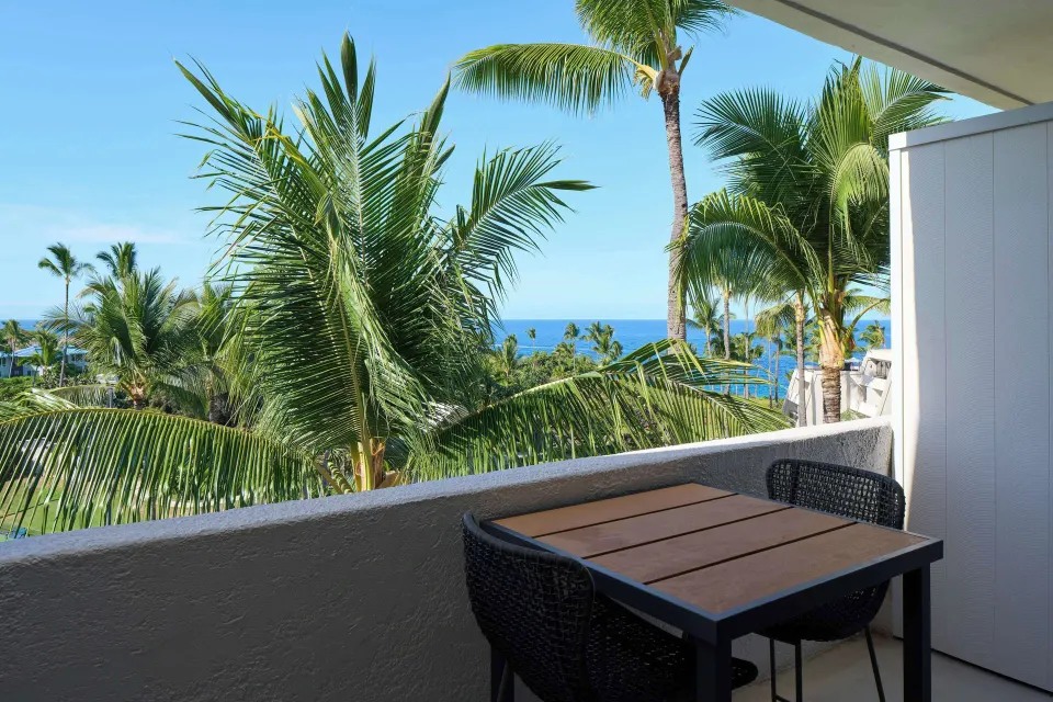 Partial ocean view room balcony with palm-framed ocean glimpse at Outrigger Kona Resort and Spa.