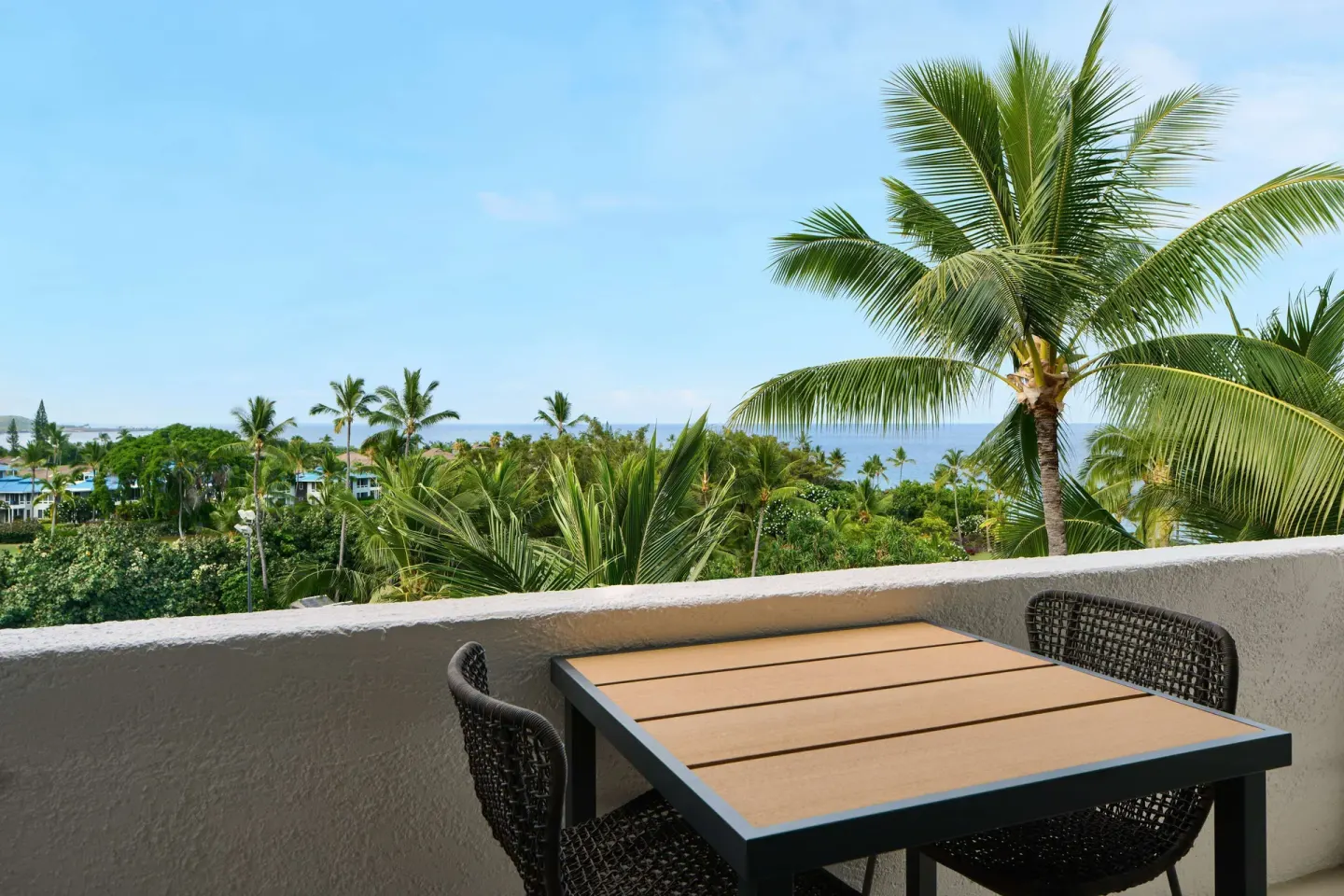 Partial ocean view room lanai with table, chairs, palms, and ocean at Outrigger Kona Resort and Spa.