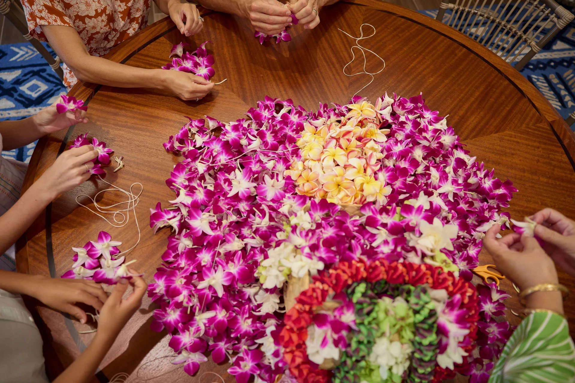 Hands string colorful flower leis at OUTRIGGER Reef Waikiki Beach Resort.
