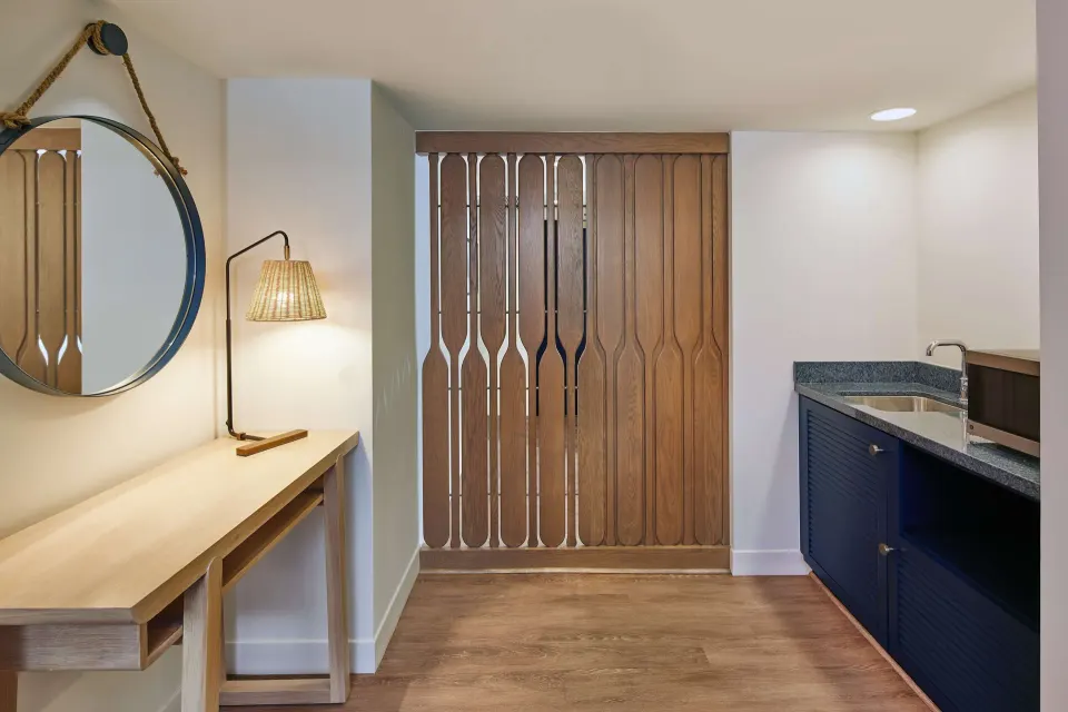 Entry wet bar with mirror, desk, sink, and wood screen at OUTRIGGER Reef Waikiki Beach Resort.