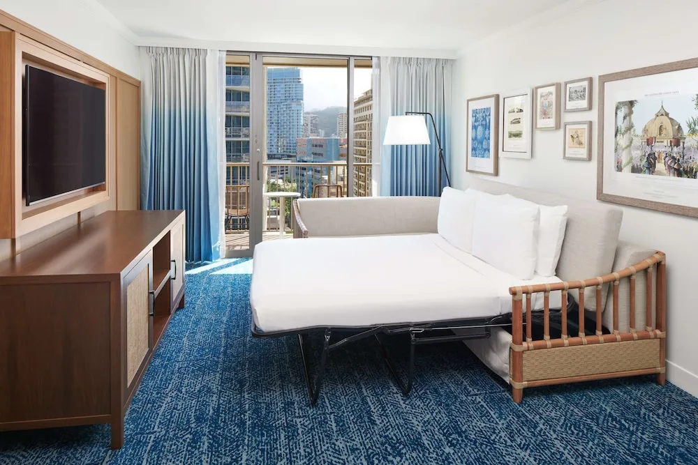 Guest room sofa bed and city balcony at OUTRIGGER Reef Waikiki Beach Resort.