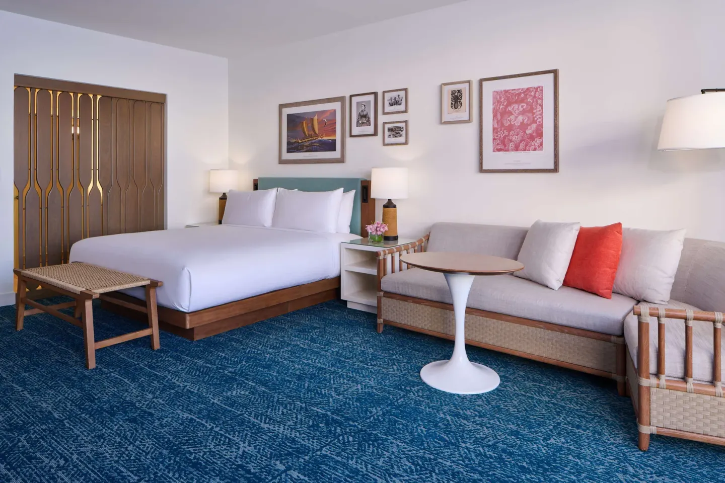 King-bed guest room with sofa and wall art at OUTRIGGER Reef Waikiki Beach Resort.