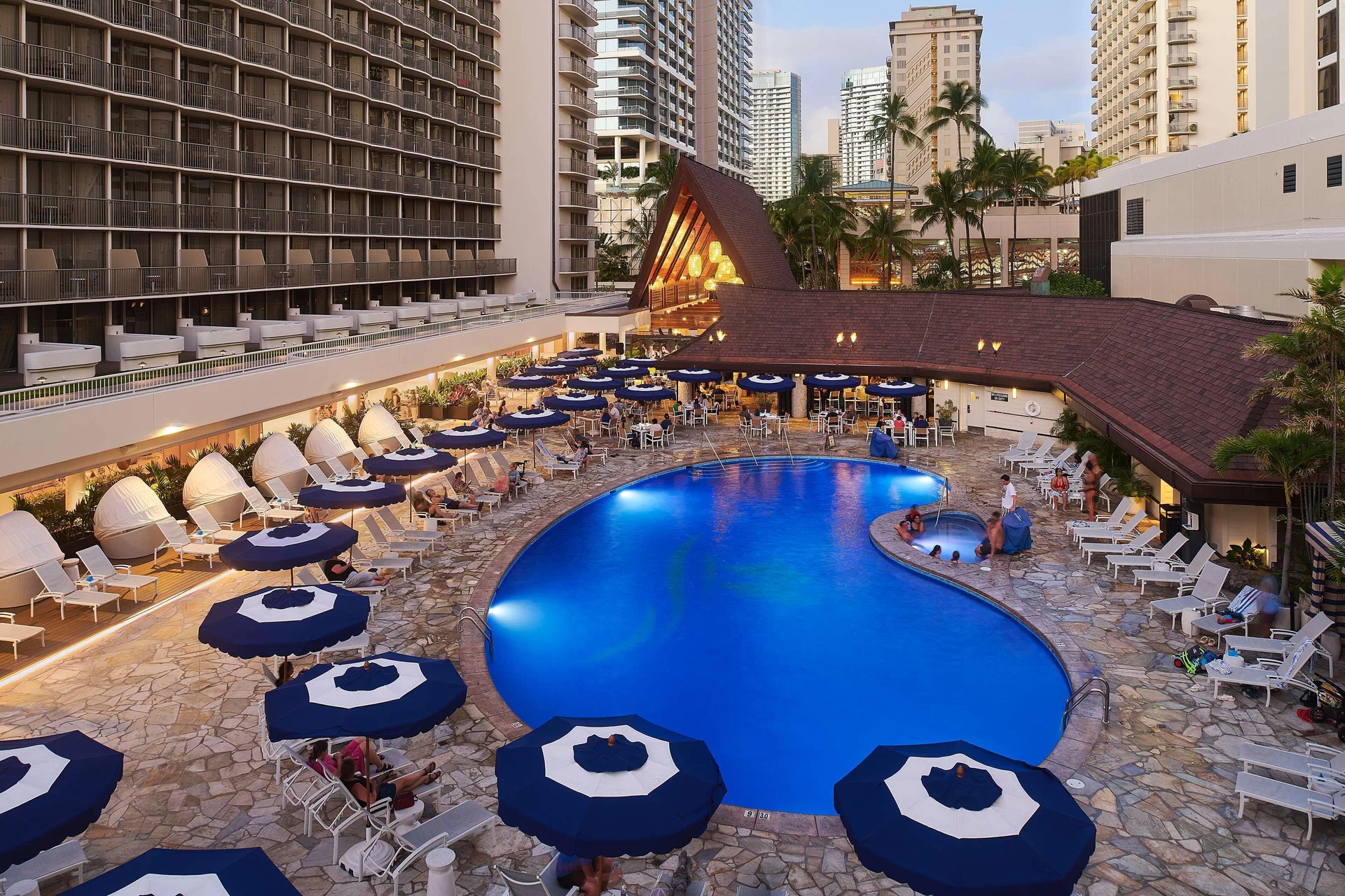 Resort pool with umbrellas and lounge chairs at OUTRIGGER Reef Waikiki Beach Resort.
