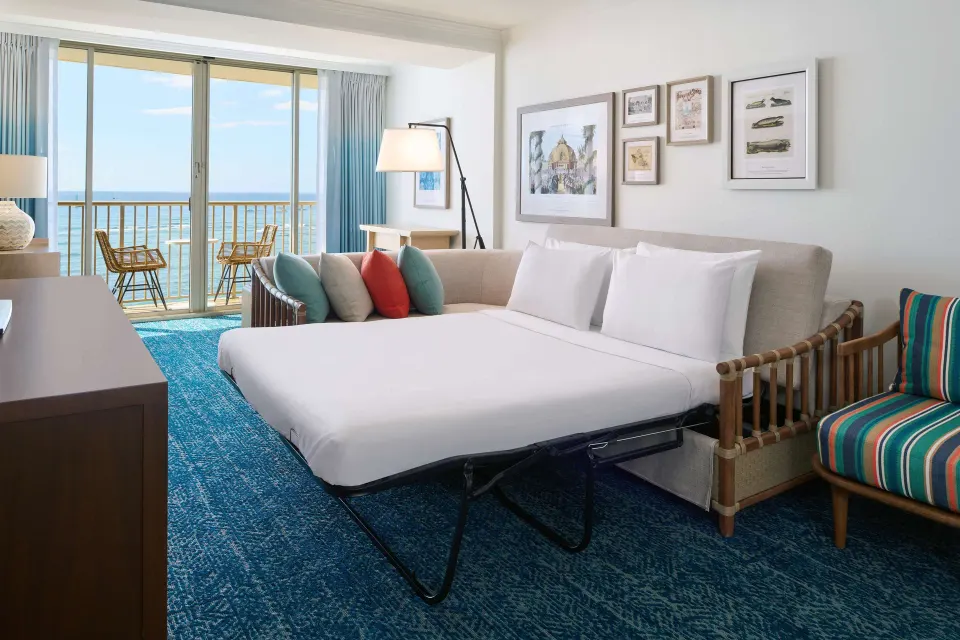 Club Suite sofa bed made up near oceanfront balcony at OUTRIGGER Reef Waikiki Beach Resort.