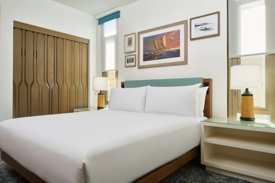 Coral Reef Penthouse Suite king bed with wood accents at OUTRIGGER Reef Waikiki Beach Resort.