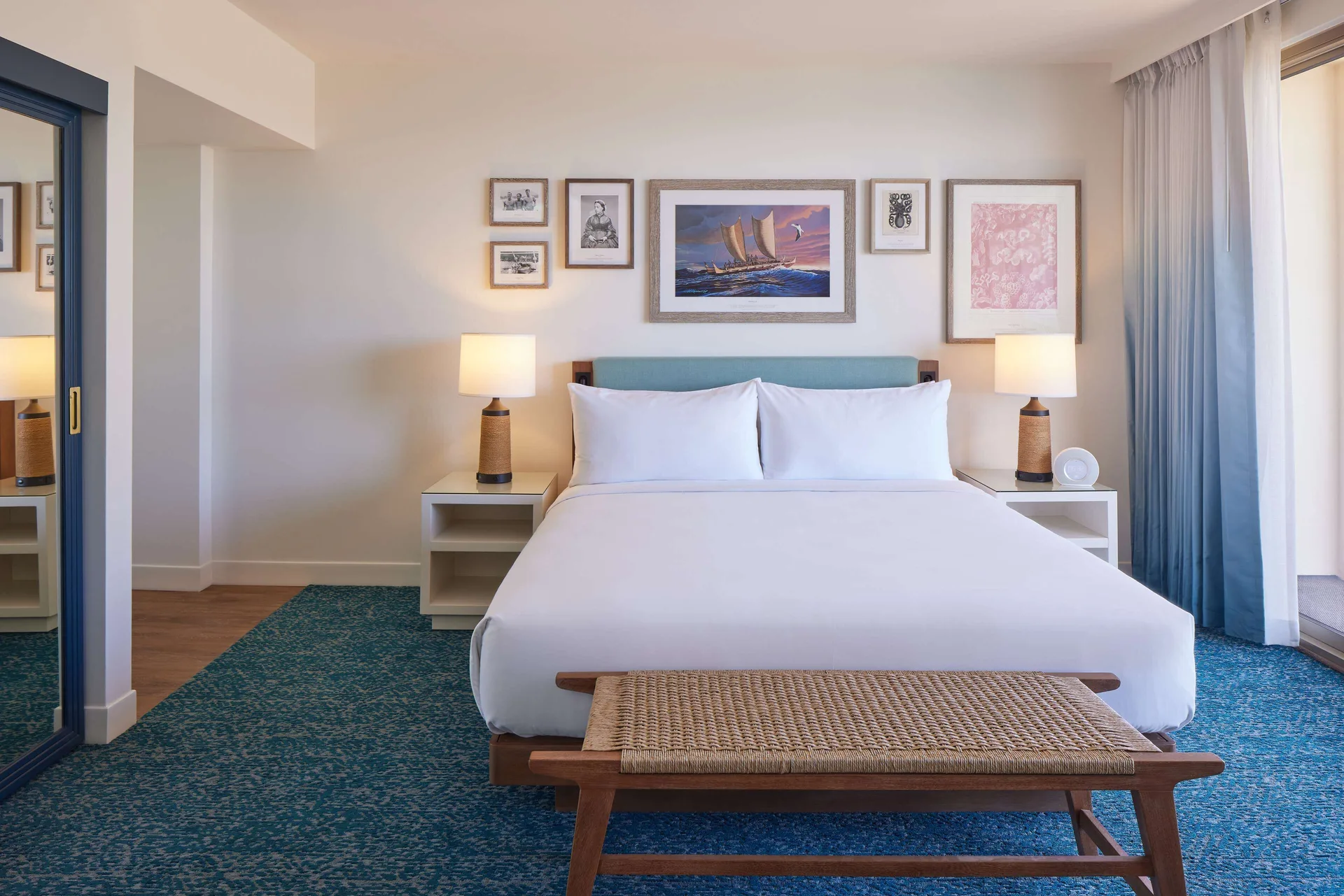 Grand Navigator Suite king bed with lamps and wall art at OUTRIGGER Reef Waikiki Beach Resort.