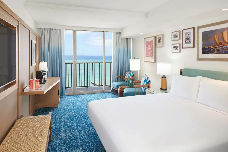 Oceanfront king room with desk, chairs, and ocean-facing balcony at OUTRIGGER Reef Waikiki Beach Resort.