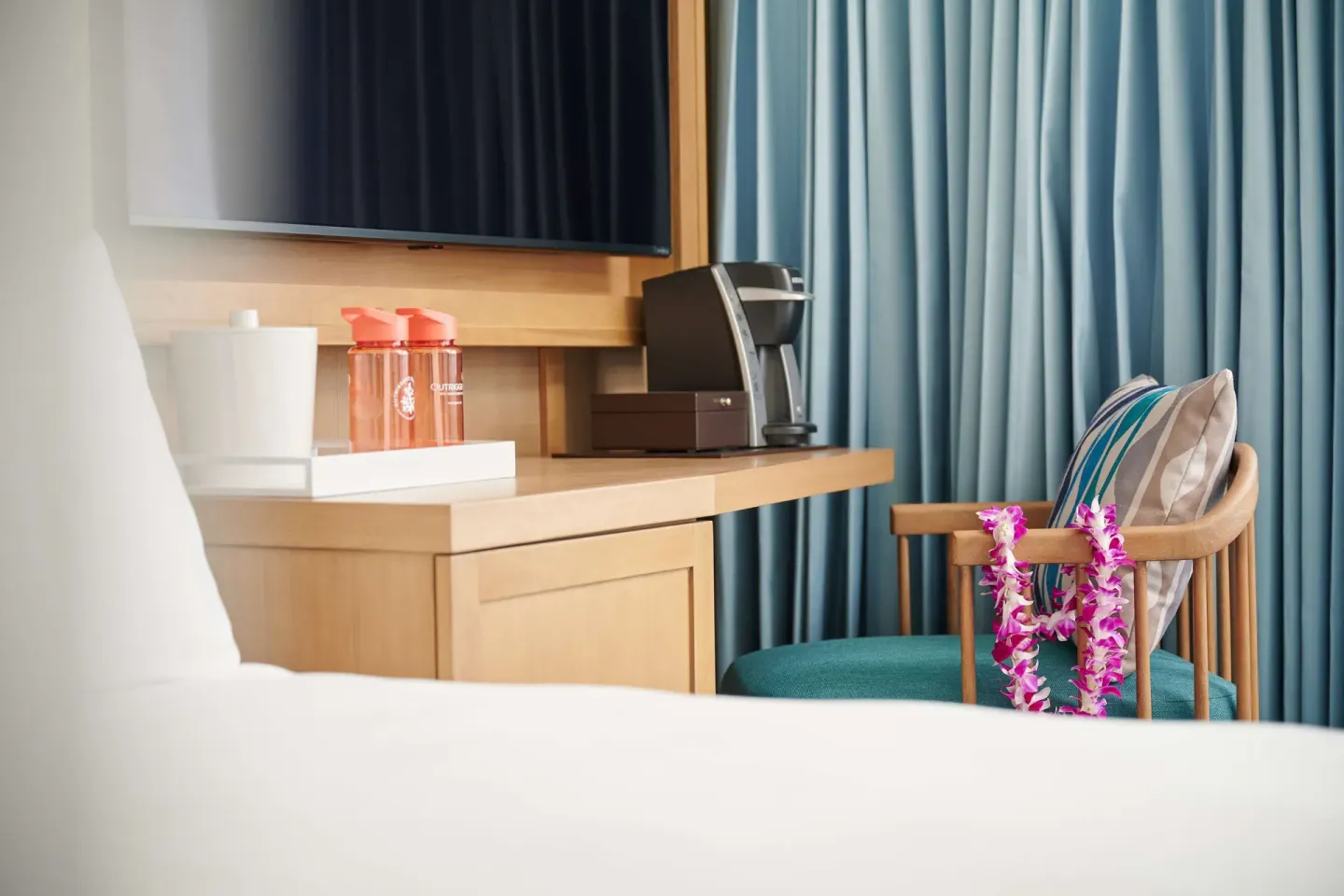 Standard Room bed, TV console and chair at OUTRIGGER Reef Waikiki Beach Resort.