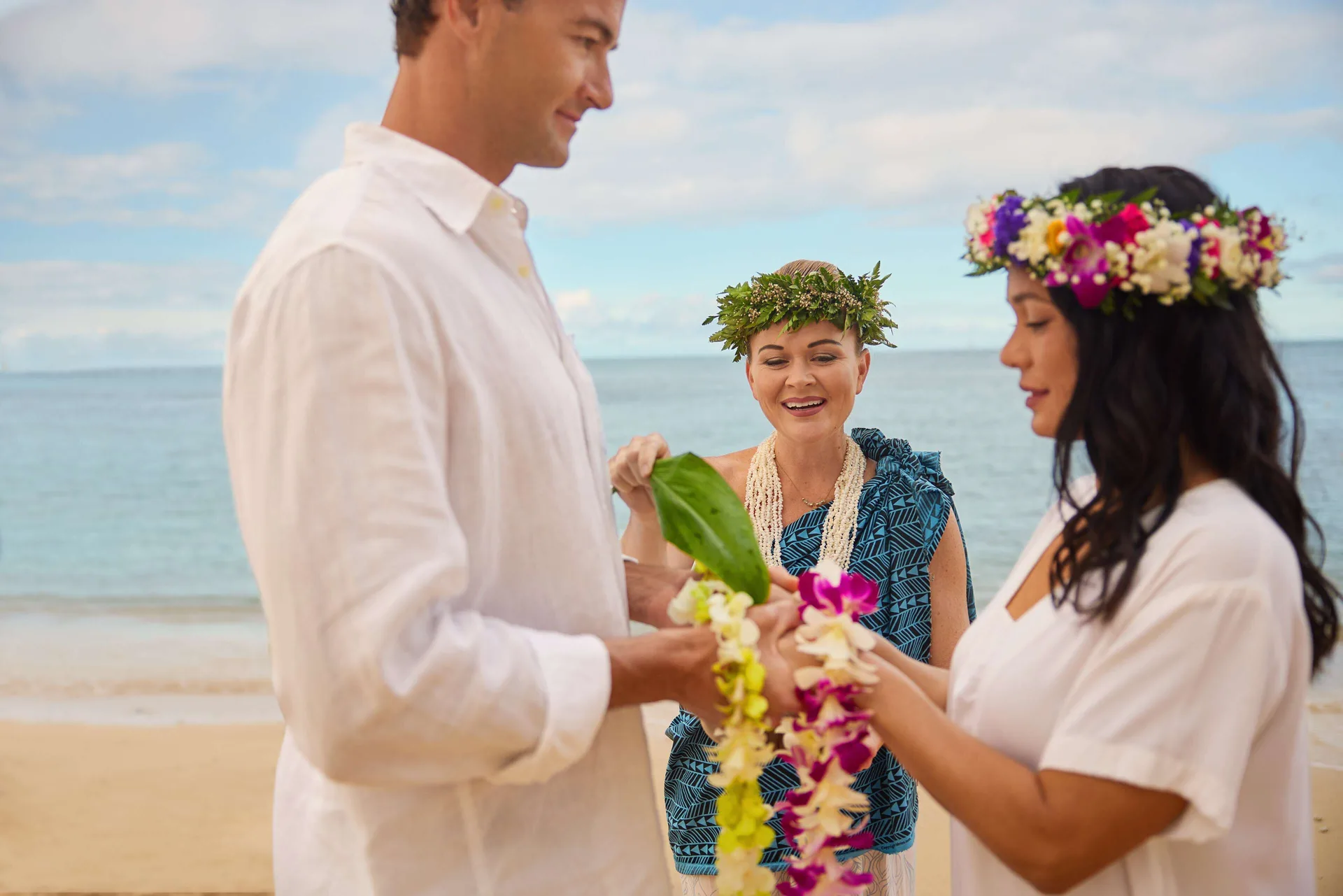 Beach wedding ceremony with floral lei exchange at OUTRIGGER Reef Waikiki Beach Resort.