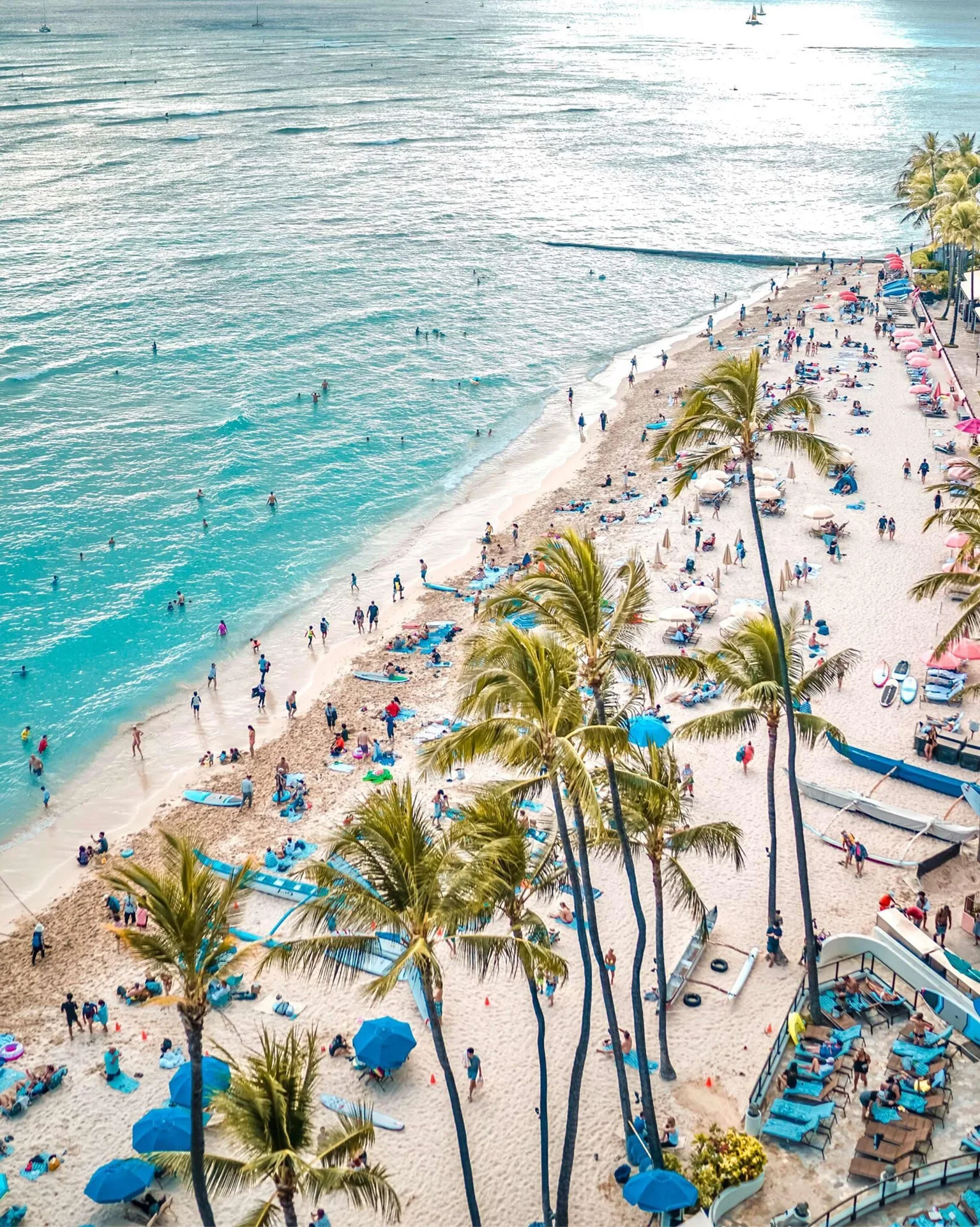 Busy Waikiki Beach with palms, swimmers, and surfboards at Outrigger Waikiki Beach Resort.