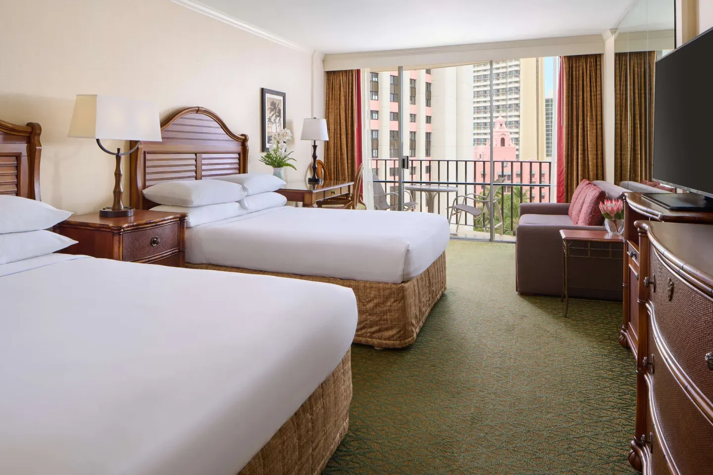 Two-bed guest room with sofa and city balcony at Outrigger Waikiki Beach Resort.