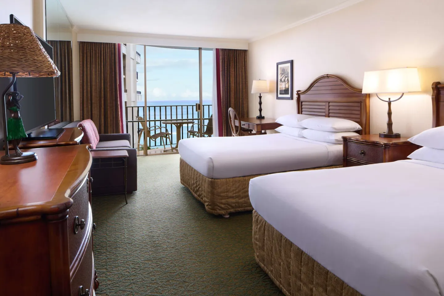 Guest room with two beds at Outrigger Waikiki Beach Resort facing a balcony and ocean view.
