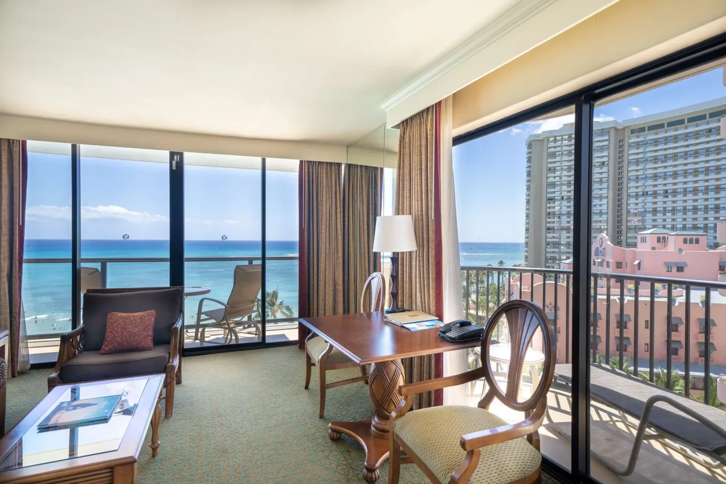 Suite living area with desk, balcony, and ocean view at Outrigger Waikiki Beach Resort.