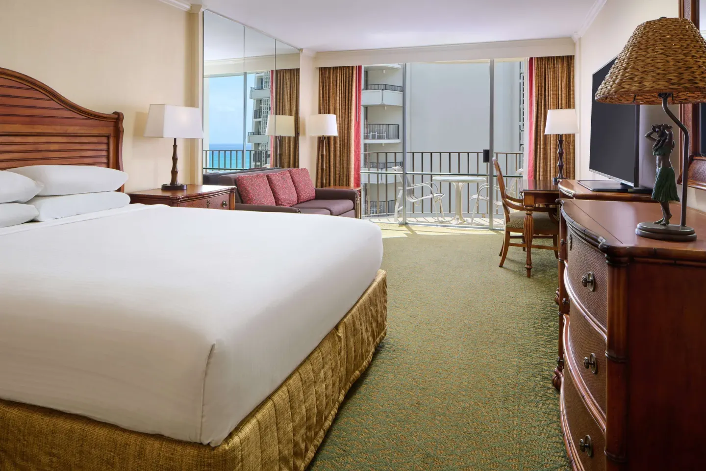 King guest room with sofa, desk, and balcony at Outrigger Waikiki Beach Resort.