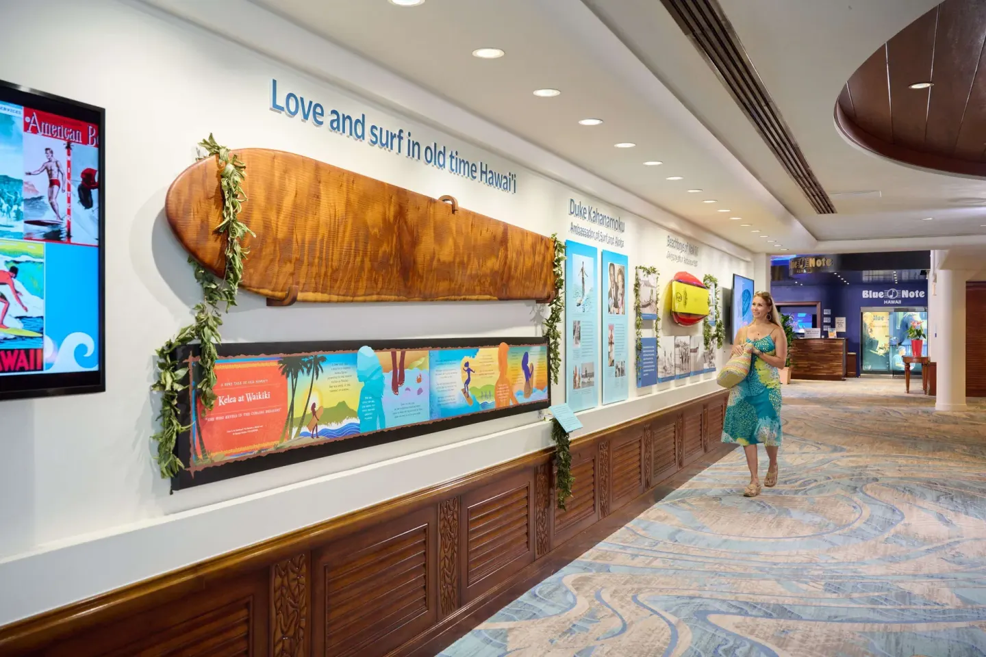 Surf history display hallway at Outrigger Waikiki Beach Resort with a long wooden board and wall exhibits.