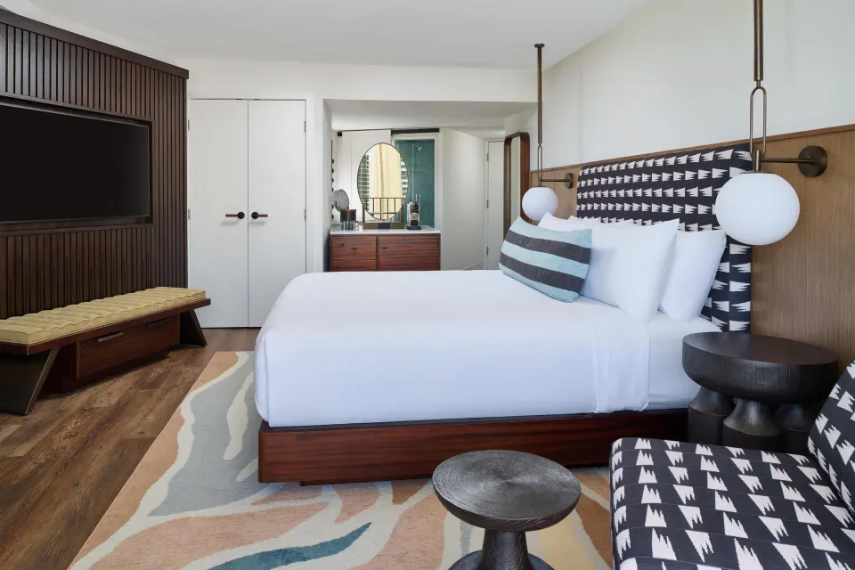 King bed, TV wall, and vanity area in a Club Room at Outrigger Waikiki Beach Resort.