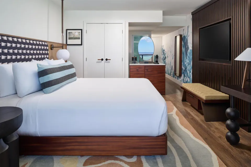 Club Room Oceanfront king bed with dresser and wall-mounted TV at Outrigger Waikiki Beach Resort.