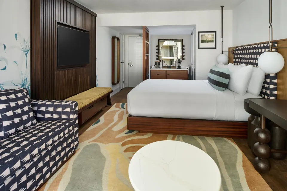 Club Room Partial Ocean View king bed with sofa and vanity at Outrigger Waikiki Beach Resort.