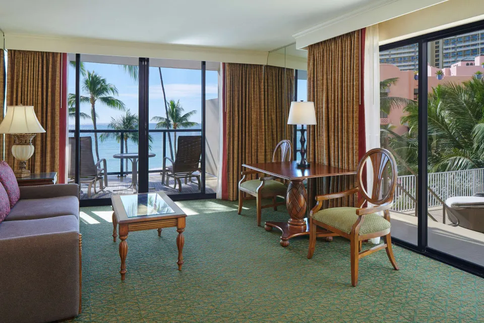 Oceanfront living area with sofa, dining table, and balcony at Outrigger Waikiki Beach Resort.